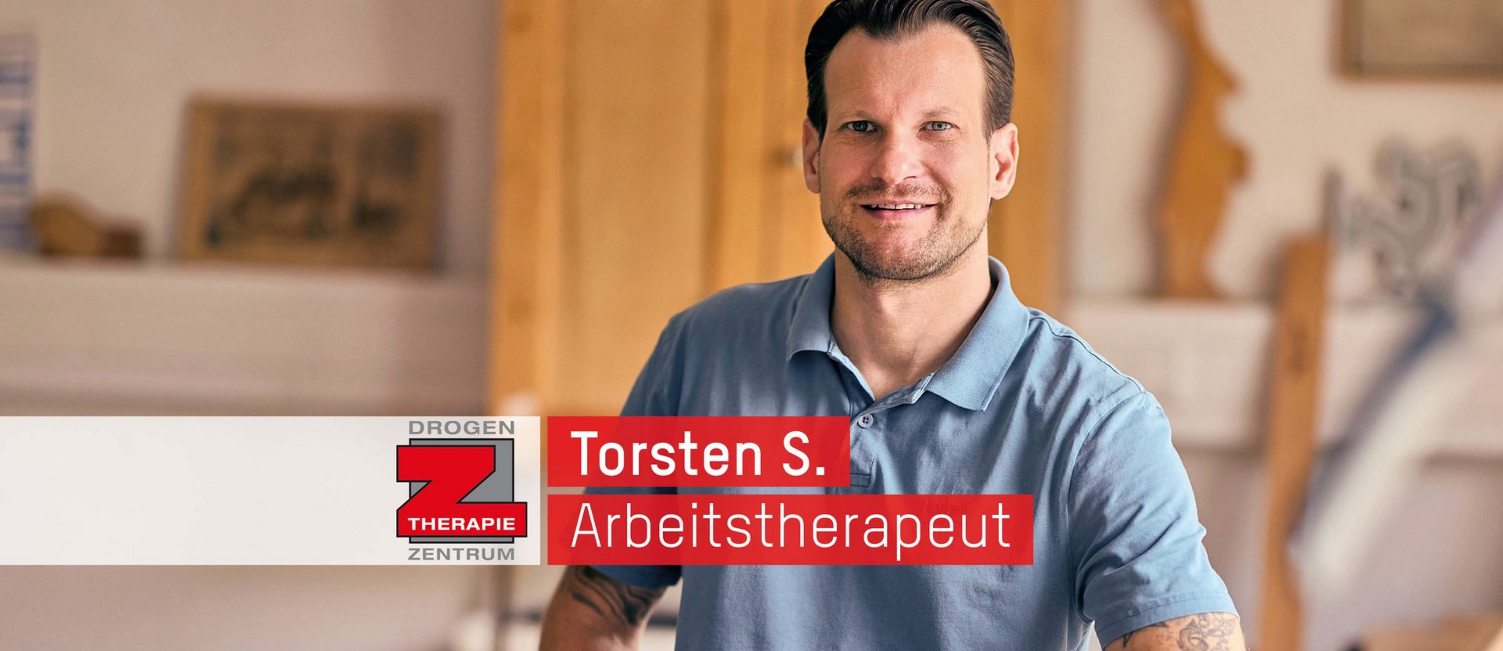 Ein lächelnder Mann in einem blauen Poloshirt steht vor einem unscharfen Hintergrund, der wie eine Werkstatt wirkt. Ein Textbanner identifiziert ihn als „Torsten S., Arbeitstherapeut“ vom „Proben Therapie Zentrum“.
