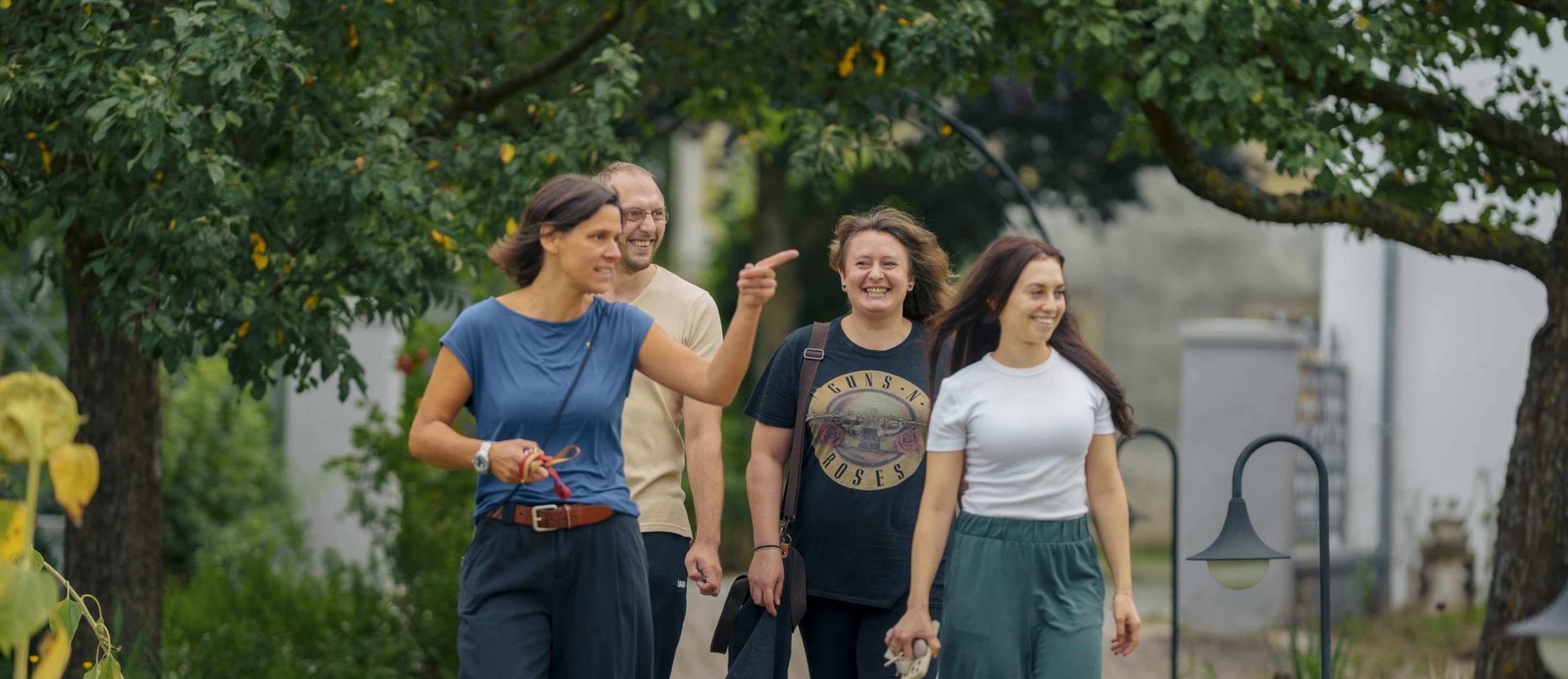 drei Frauen und ein Mann gehen zusammen draussen spazieren 